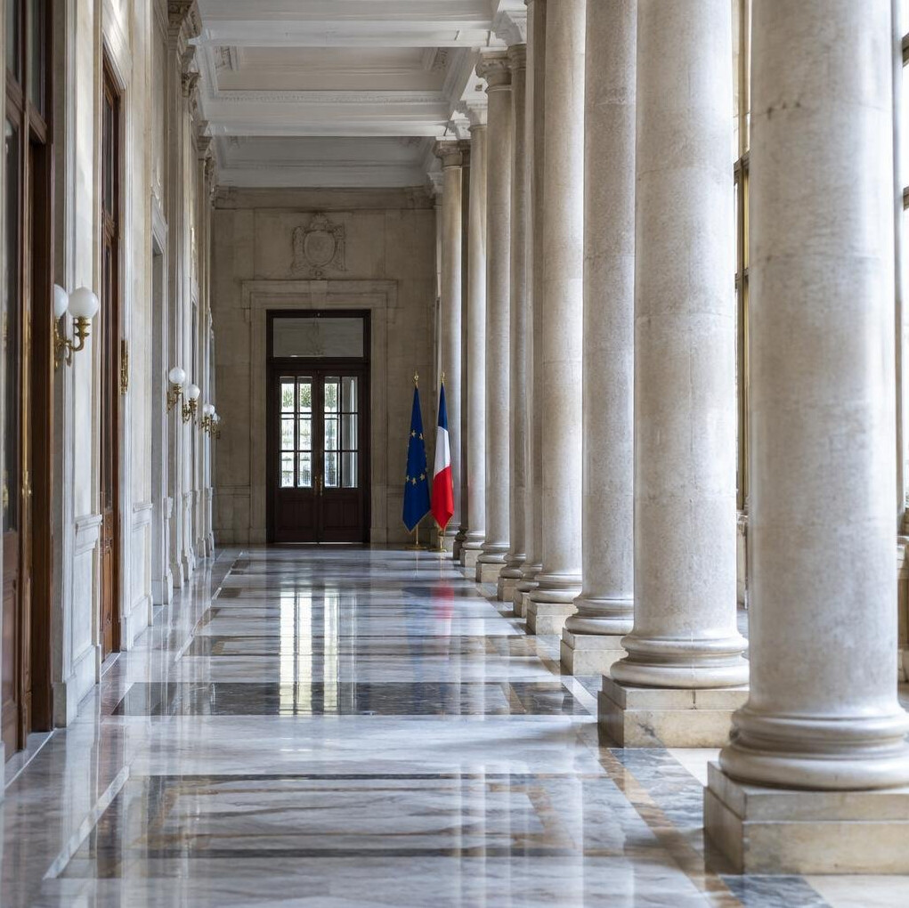 Corredor de um edifício institucional europeu com colunas clássicas